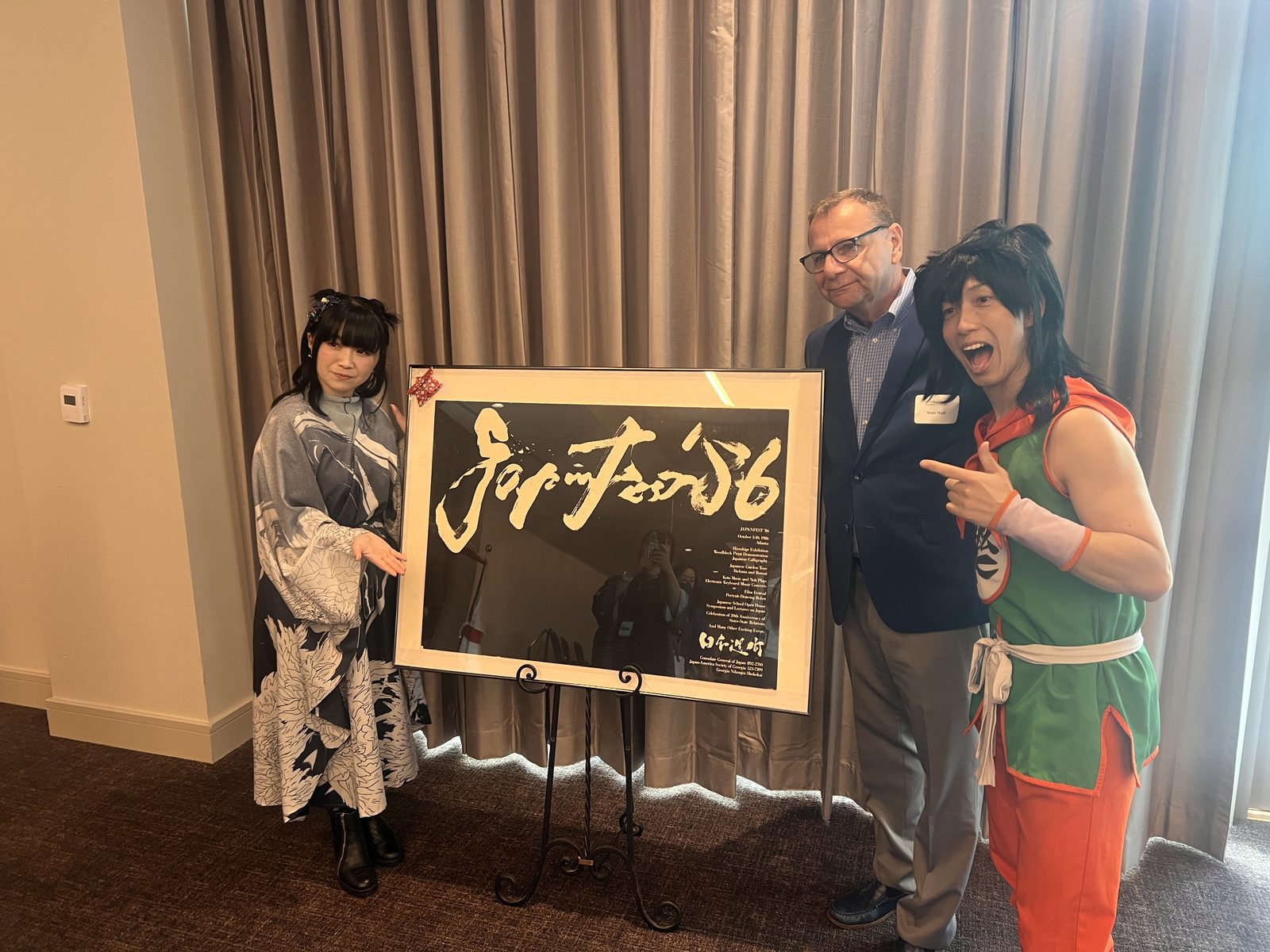 VIPカンファレンス会場の JapanFest '86 記念額と野水伊織さん、バードフミヤさん